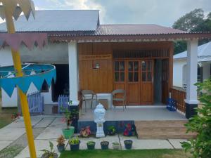 Homestay Melty Aprianti Tanjong Tinggi في Pasarbaru: منزل مع شرفة مع طاولة وكراسي
