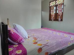 um quarto com uma cama rosa com almofadas e uma janela em Homestay Melty Aprianti Tanjong Tinggi em Pasarbaru