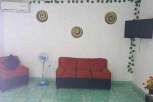 ein Wohnzimmer mit einem roten Sofa und einem Ventilator in der Unterkunft Apto Yori: amplio y equipado. in Mérida