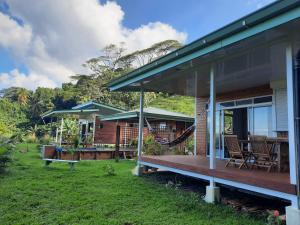 a house with a porch and chairs on the grass at Fare Juanita Piti in Opoa