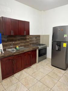 eine Küche mit Holzschränken und einem Kühlschrank aus Edelstahl in der Unterkunft EMMA HOUSE in Puerto Baquerizo Moreno