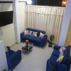 sala de estar con sofás azules y TV en El Jardín de la Bella, en Tingo María