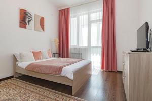 a bedroom with a bed with red curtains and a television at Уютная Квартира Expo Boulevar in Astana