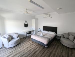 a bedroom with a bed and two chairs at Escape On Lake in Cairns