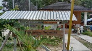 Homestay Suryati Tanjong Tinggi في Pasarbaru: شرفة مع علامة في الحديقة