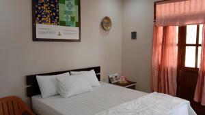 Homestay Suryati Tanjong Tinggi في Pasarbaru: غرفة نوم بسرير وساعة على الحائط