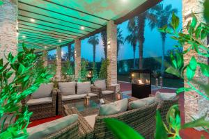 a patio with wicker furniture and palm trees at night at Holiday Inn Kuwait by IHG in Kuwait