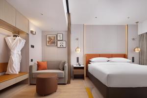 成都市にあるHome2 Suites by Hilton Chengdu Kuanzhai Alleyのベッドと椅子付きのホテルルーム