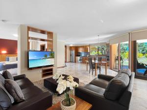 a living room with two couches and a tv at Aurora Cottages Bush Retreat in Halls Gap