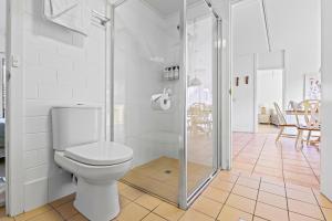 a bathroom with a toilet and a glass shower at The Islander in Point Lookout