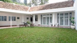 uma casa branca com um relvado no quintal em The Wastoekentjana em Bandung
