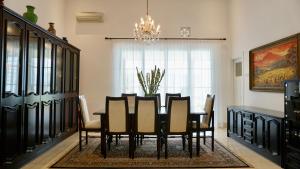 una sala da pranzo con tavolo, sedie e lampadario pendente di The Wastoekentjana a Bandung
