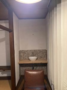 a bathroom with a sink and a brown chair at Hotel shirahama in Shirahama