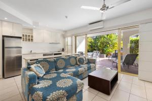 a living room with a blue couch and a kitchen at French Quarter Apartment 116, Noosa Heads in Noosa Heads
