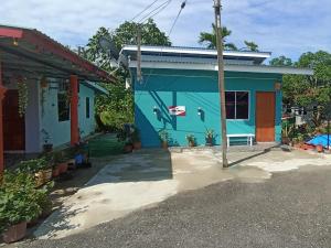 a blue house with a palm tree in front of it at Haji Ineng Homestay- Guest House in Kota Samarahan