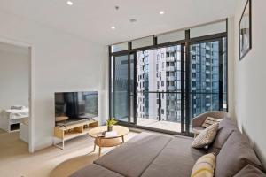 a living room with a couch and a large window at Southbank Apartment with Skyline View: 5-Min Walk to CROWN Casino in Melbourne