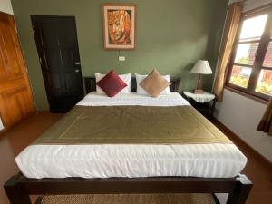 um quarto com uma cama grande com almofadas em Baan Klang Vieng em Chiang Mai