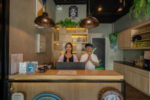 two women standing behind a counter with a laptop at Patong Poshtel in Patong Beach