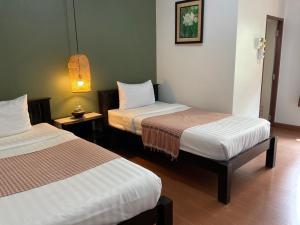 a hotel room with two beds and a lamp at Baan Klang Vieng in Chiang Mai