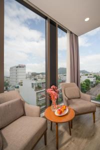 ein Wohnzimmer mit einem Tisch, Stühlen und Fenstern in der Unterkunft RAON Hotel - STAY 24H in Quy Nhon