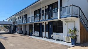 un bâtiment avec des tables et des chaises à l'extérieur dans l'établissement Moffat Beach Motel Caloundra, à Caloundra