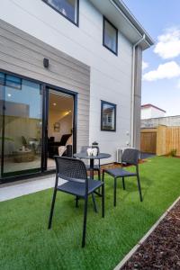 a patio with two chairs and a table on grass at Coastal Sands Escape 1 bed 1 bath w/sofa bed in Christchurch