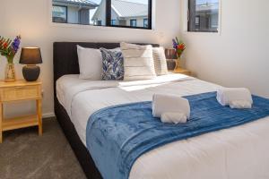 a bedroom with a large bed with a blue blanket at Coastal Sands Escape 1 bed 1 bath w/sofa bed in Christchurch