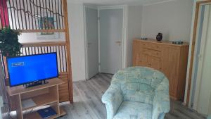 a living room with a tv and a couch with a chair at Haus Katharina in Loissin