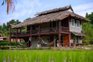 una casa con techo de paja y porche en เฮินไต รีสอร์ท แม่ลาน้อย, en Ban Mae La Noi