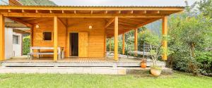 a wooden cabin with a bench on a deck at Le cottage in La Plaine des Palmistes