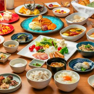 stół z wieloma talerzami jedzenia w obiekcie Kobe Hotel Juraku w mieście Kobe