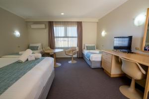 a hotel room with two beds and a desk at Hospitality Carnarvon, SureStay Collection by Best Western in Carnarvon