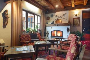 sala de estar con chimenea, mesas y sillas en Hotel Dolomites Inn, en Canazei