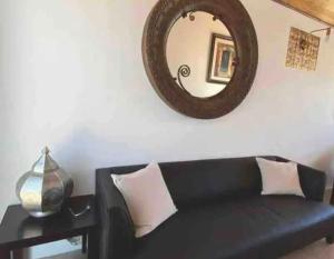 um sofá preto com um espelho na parede em las palmas em Ensenada