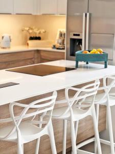 una cocina con 2 sillas blancas y una mesa con fruta. en Luxury 4 Bed Penthouse, Pool & stunning Sea views en Grand Baie