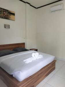 a bed with a white towel on top of it at Gio's Place in Labuan Bajo