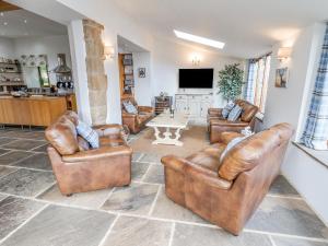 a living room with leather furniture and a flat screen tv at The Gatehouse in Sutton in Ashfield