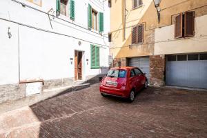 ein rotes Auto, das auf einer Backsteinstraße neben Gebäuden parkt in der Unterkunft The Sunflower in Siena