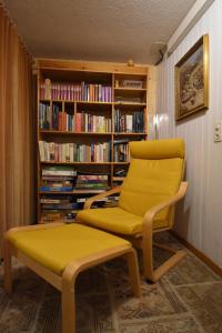 una silla amarilla y un banco frente a una estantería de libros en Bonis 2,5 Zimmer Ferienwohnung, en Eschenz