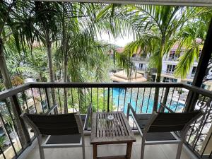 a balcony with a table and chairs and a pool at Baan Karon Resort in Karon Beach