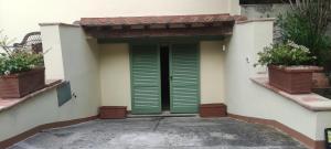 a green door on the side of a building at Bilocale a due passi dal mare immerso nel verde in Castiglioncello