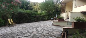 a stone patio with chairs and plants in a yard at Bilocale a due passi dal mare immerso nel verde in Castiglioncello