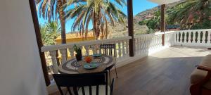 d'un balcon avec une table, des chaises et des palmiers. dans l'établissement Vv Casa Zoila, à Vallehermoso