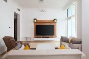 sala de estar con sofá y TV de pantalla plana en Dubai Marina 2BR Beach Oasis en Dubái