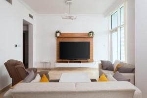 uma sala de estar com um sofá e uma televisão de ecrã plano em Dubai Marina 2BR Beach Oasis no Dubai