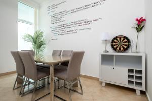 a dining room table with chairs and a dartboard on the wall at Dubai Marina 2BR Beach Oasis in Dubai