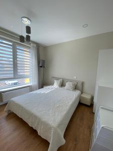 a white bedroom with a bed and a window at Apartment Fontanu Namai in Vilnius
