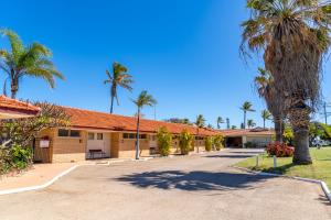 a building with palm trees and a street at Hospitality Carnarvon, SureStay Collection by Best Western in Carnarvon