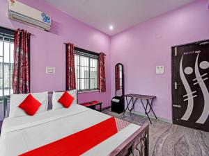 een slaapkamer met roze muren en een bed met rode kussens bij Urvashi Guest House in Durgapur