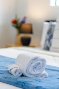 a white towel on a bed with a blue rug at Coastal Sands Escape 1 bed 1 bath w/sofa bed in Christchurch